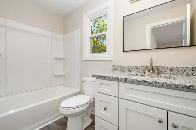 a bathroom with a granite countertop toilet sink and mirror