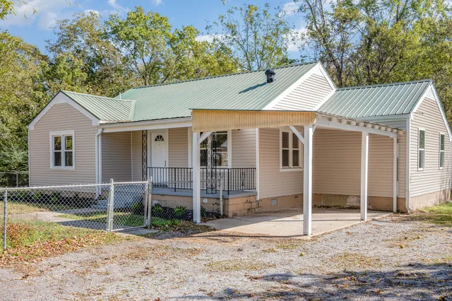 a view of a white house with a yard and large tree