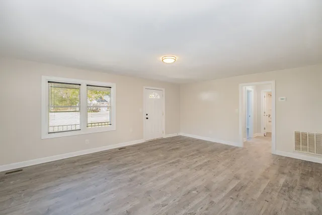 an empty room with wooden floor and windows