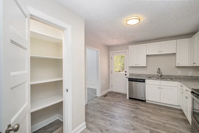 a kitchen with granite countertop a sink stove and cabinets