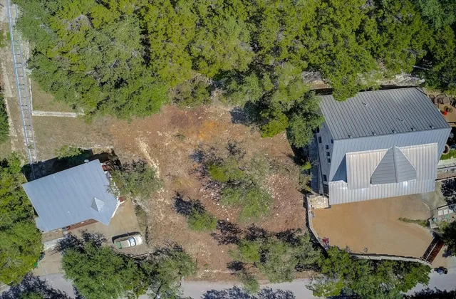 an aerial view of a house with yard and trees in the background