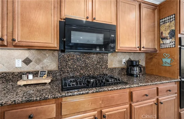 a kitchen with granite countertop a sink a stove and a microwave