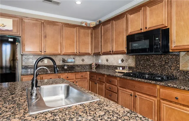 a kitchen with stainless steel appliances granite countertop a sink a stove a microwave a sink and cabinets
