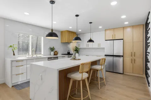 a kitchen with stainless steel appliances granite countertop a sink a stove a refrigerator and island with wooden floor