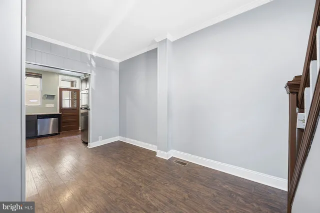 an empty room with wooden floor and a bathroom