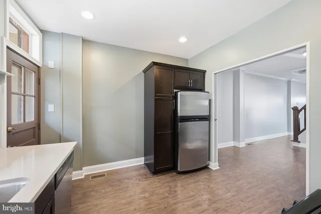 a view of a refrigerator in kitchen and an empty room