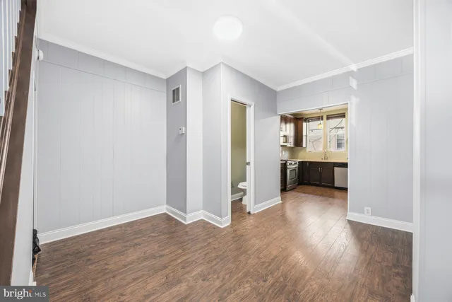 an empty room with wooden floor cabinet and windows