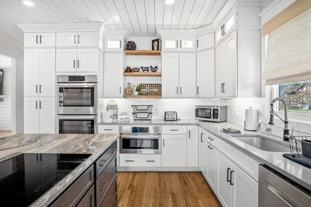 a kitchen with stainless steel appliances white cabinets and a stove top oven