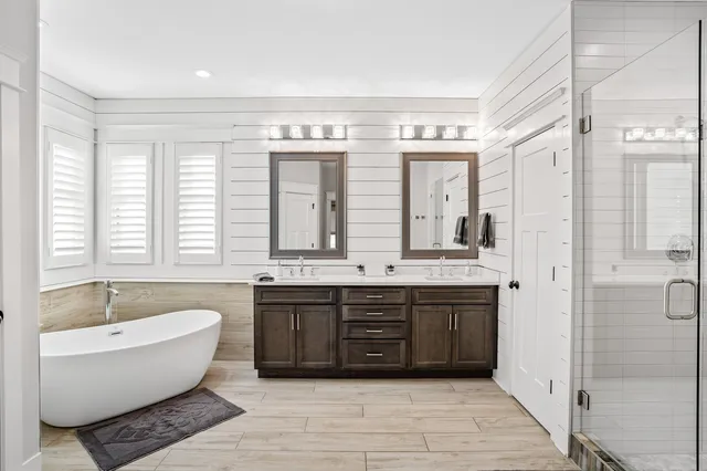 a spacious bathroom with a double vanity sink large mirror and a bathtub