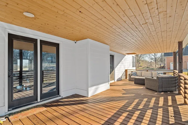 a view of a patio with couches plants and wooden floor