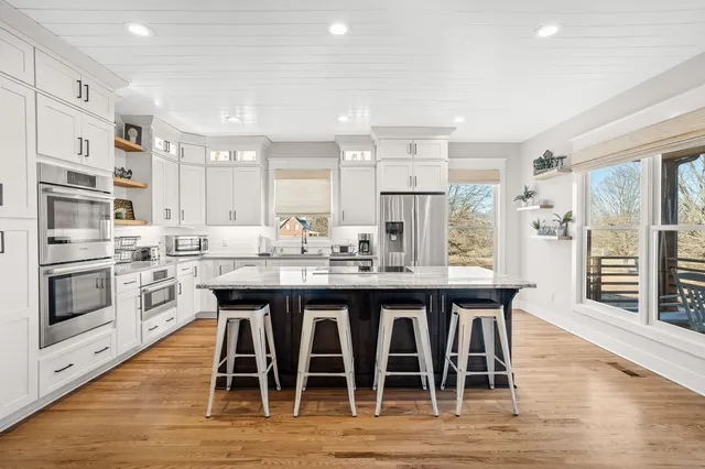 a kitchen with stainless steel appliances granite countertop a table chairs sink and cabinets
