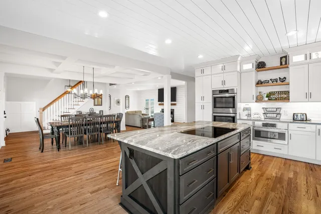 a kitchen with stainless steel appliances granite countertop a stove oven a dining table and chairs with wooden floor