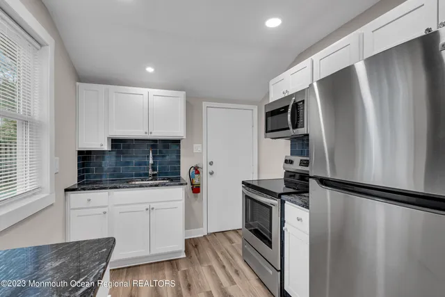 a kitchen with granite countertop a refrigerator stove and sink