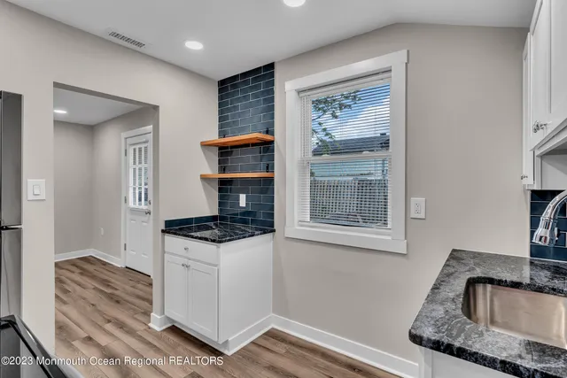a kitchen with granite countertop a sink stove and cabinets