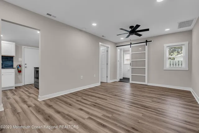 a view of empty room with wooden floor and ceiling fan