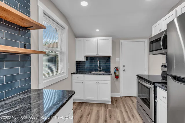 a kitchen with granite countertop a stove and a wooden floor