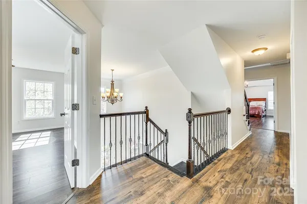 a view of a hallway with wooden floor and windows