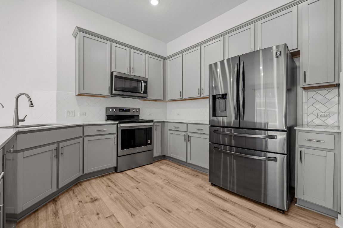 1120 Bear Track Loop Georgetown, TX 78628 - Photo 10 of 26 Kitchen with gray cabinets, stainless steel appliances, backsplash, light wood-type flooring, and recessed lighting