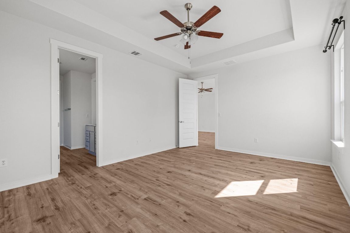 1120 Bear Track Loop Georgetown, TX 78628 - Photo 12 of 26 Unfurnished bedroom with a raised ceiling, light wood finished floors, and ceiling fan