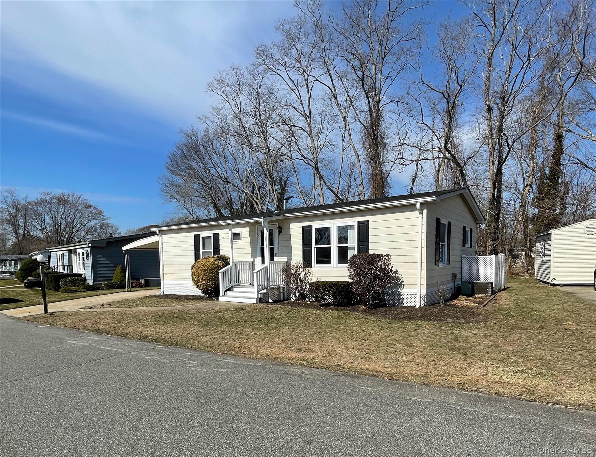 1661 Old Country Road, Unit 398 Riverhead, NY 11901 - Photo 2 of 14 a front view of house with yard and trees in the background
