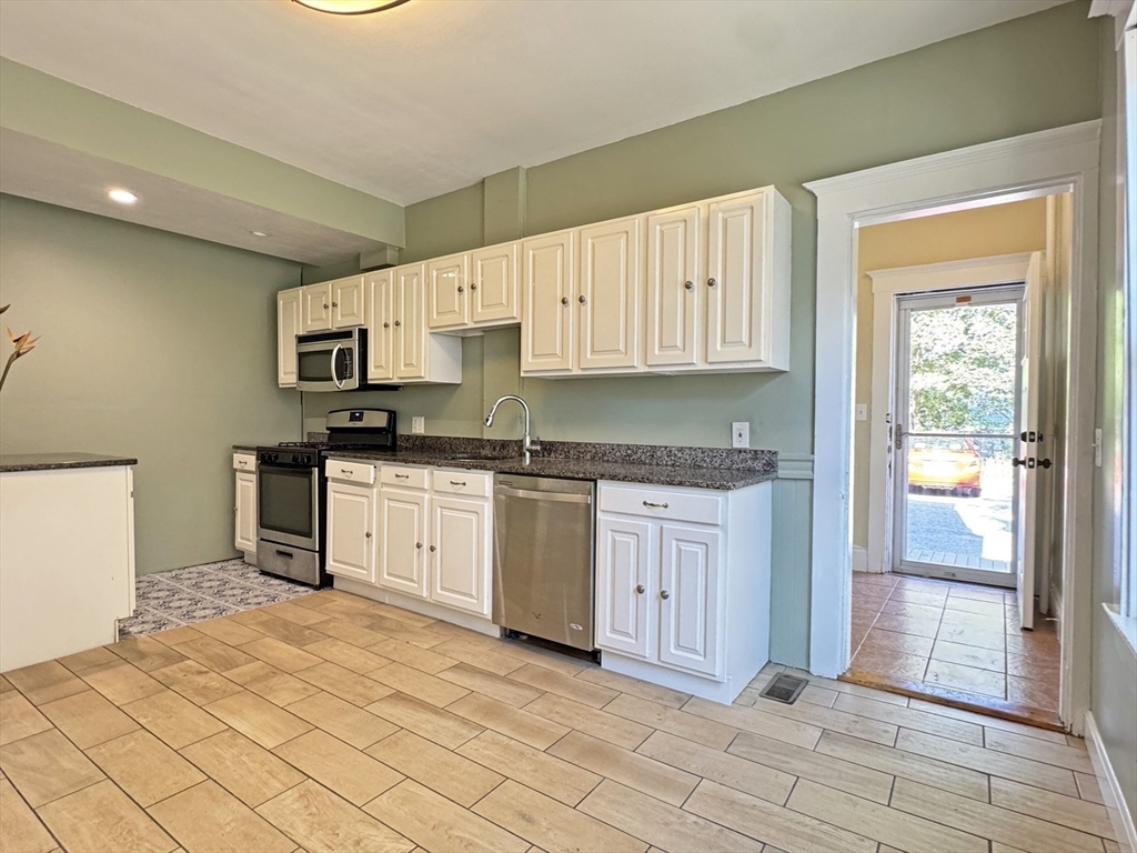 48 Harvard Street, Unit 1 Newton, MA 02460 - Photo 12 of 32 a kitchen with granite countertop a stove top oven sink and cabinets