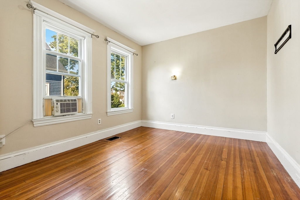 48 Harvard Street, Unit 1 Newton, MA 02460 - Photo 18 of 32 a view of an empty room with wooden floor and a window
