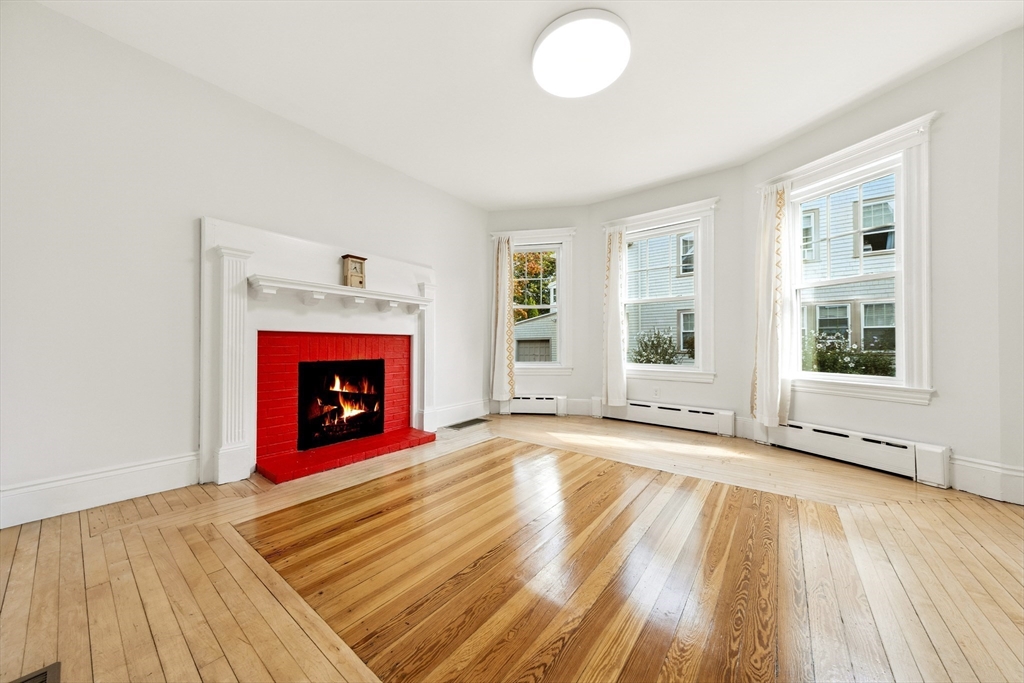 48 Harvard Street, Unit 1 Newton, MA 02460 - Photo 7 of 32 a view of empty room with wooden floor and fireplace
