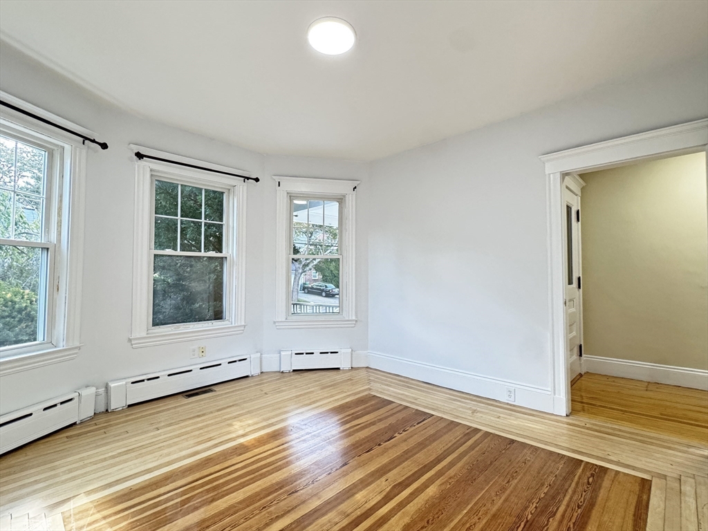 48 Harvard Street, Unit 1 Newton, MA 02460 - Photo 10 of 32 an empty room with wooden floor and windows