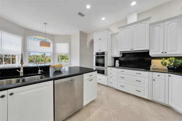 a kitchen with stainless steel appliances granite countertop a sink and white cabinets