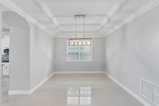 an empty room with windows and chandelier fan