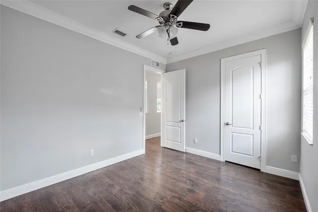 an empty room with wooden floor and ceiling fan