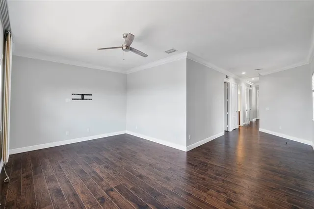 a view of an empty room with wooden floor and a ceiling fan
