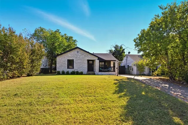 a front view of house with yard and trees in the background