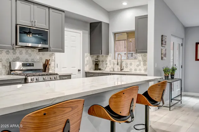 a kitchen with stainless steel appliances granite countertop a stove a sink and a microwave