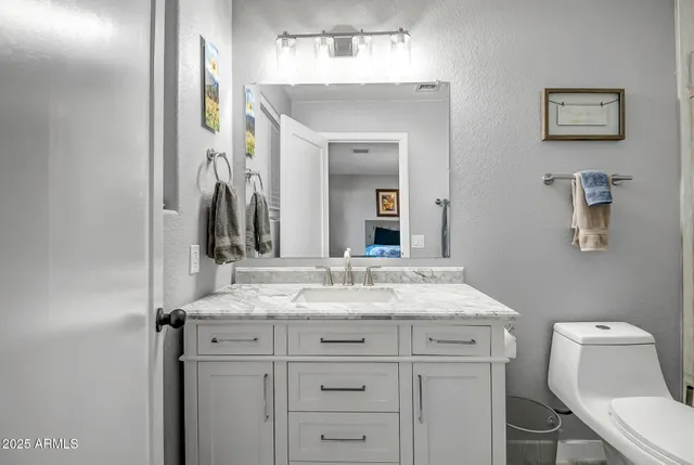 a bathroom with a granite countertop sink vanity mirror and toilet