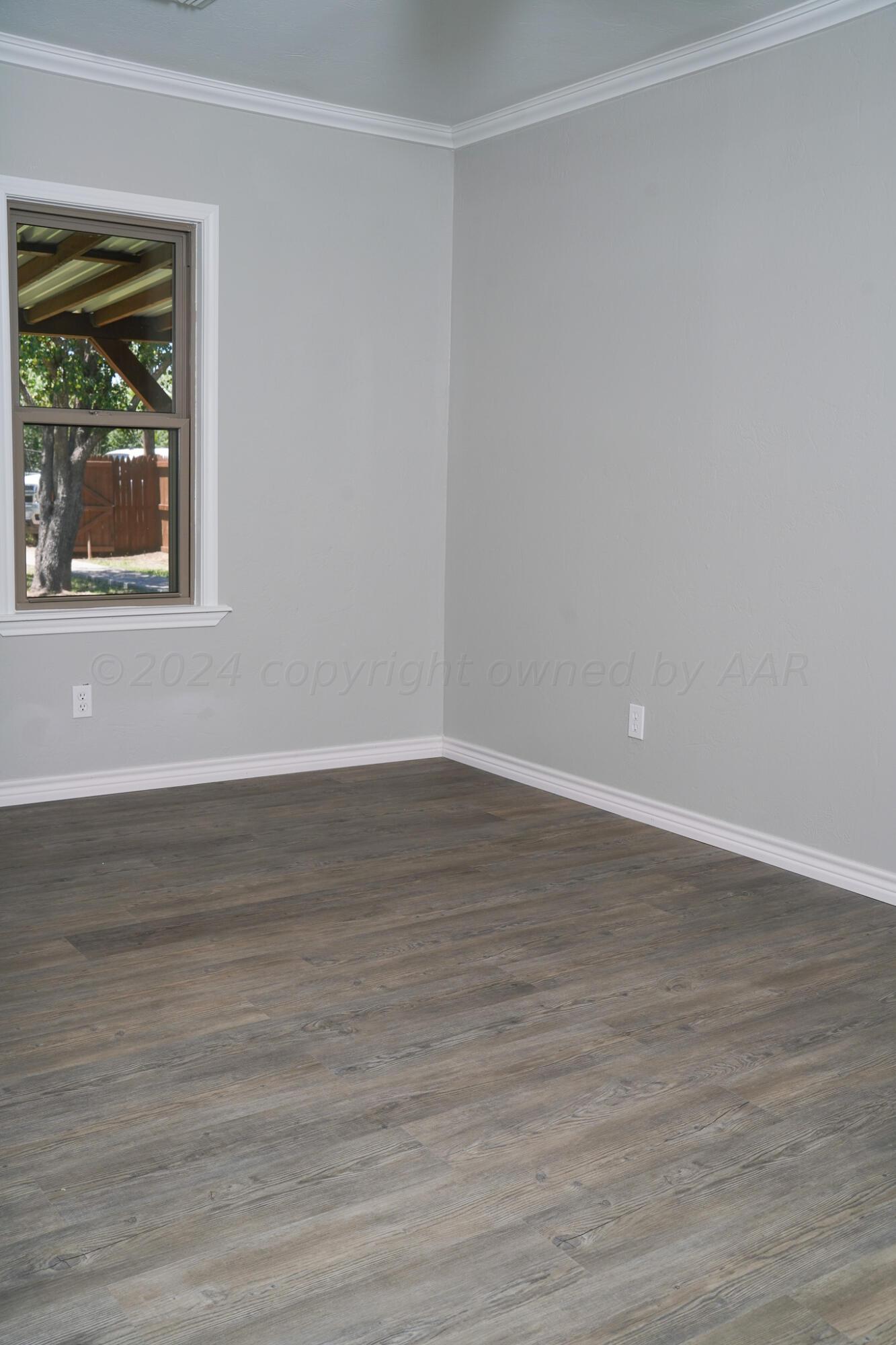 709 North Wells Street Pampa, TX 79065 - Photo 16 of 26 a view of an empty room with wooden floor and a window