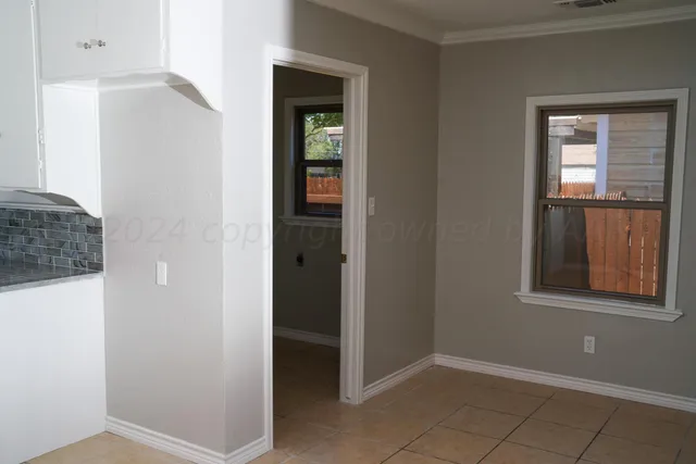 a view of an empty room with closet and a window