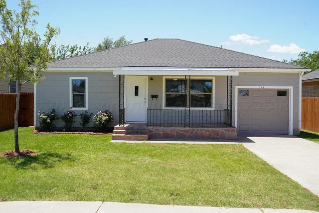 a view of a house with a yard and potted plants