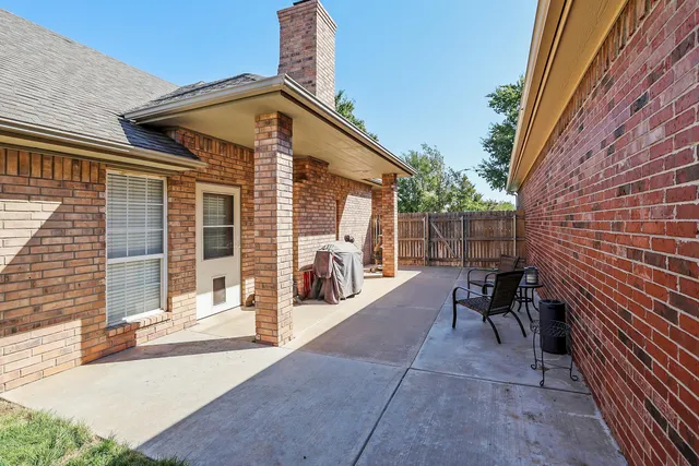 a view of a patio with table and chairs and wooden fence