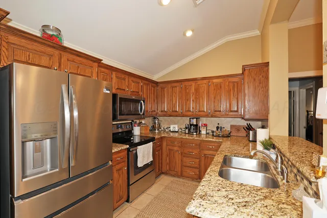 a kitchen with kitchen island granite countertop a refrigerator stove and sink