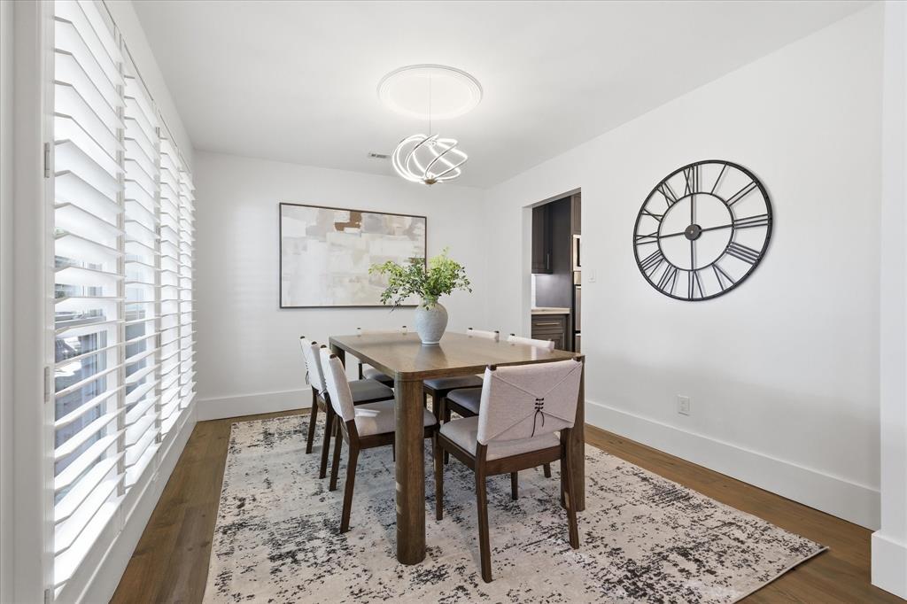 4310 Forest Bend Road Dallas, TX 75244 - Photo 9 of 40 Dining area featuring wood-finish flooring, white plantation shutters, a contemporary chandelier, and crisp white walls