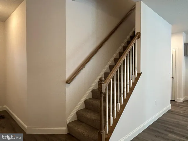 a view of staircase with wooden floor and white walls