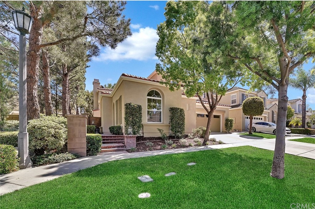 a front view of a house with garden and trees