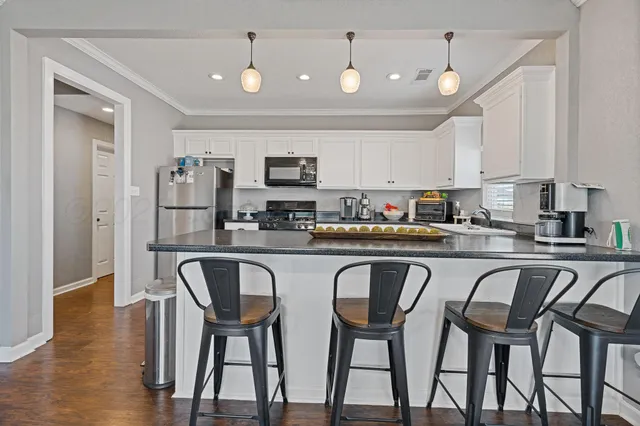 a kitchen with stainless steel appliances granite countertop a table chairs microwave and sink