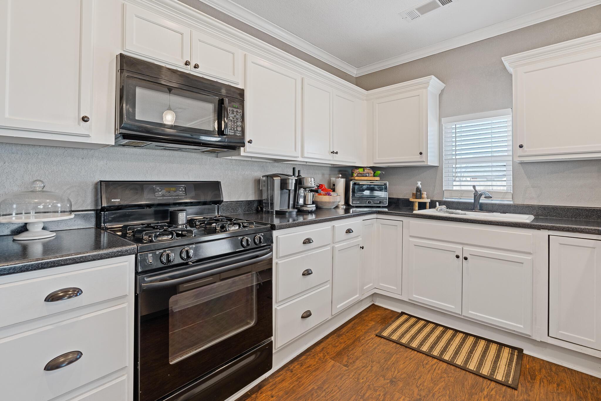 104 South Cherry Street Claude, TX 79019 - Photo 13 of 22 a kitchen with stainless steel appliances granite countertop grey cabinets a stove a sink and dishwasher