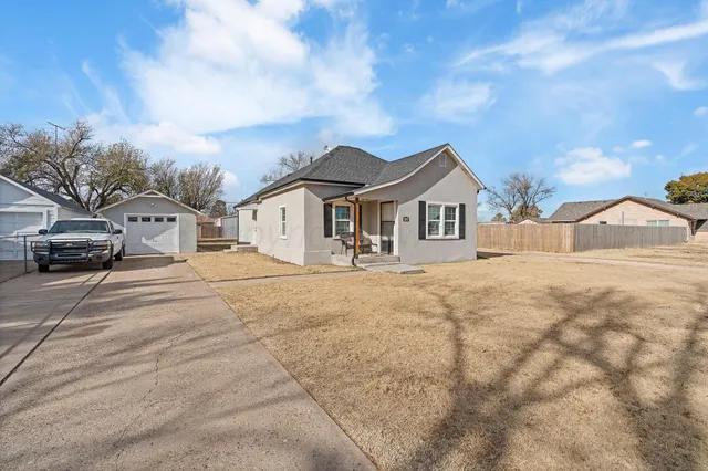 a view of a white house with a large tree in front of it