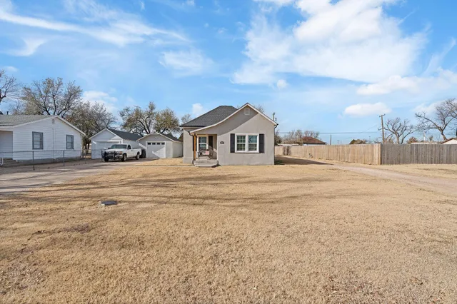 a view of white house with a big yard and large trees