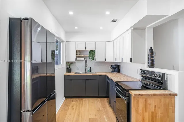 a kitchen with stainless steel appliances granite countertop a refrigerator a stove and a sink