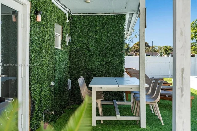 a patio with table and chairs and potted plants
