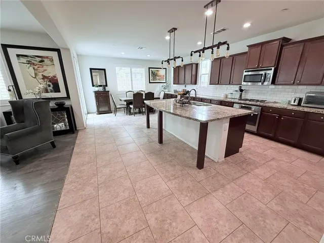 a large white kitchen with lots of counter space dining table and stainless steel appliances